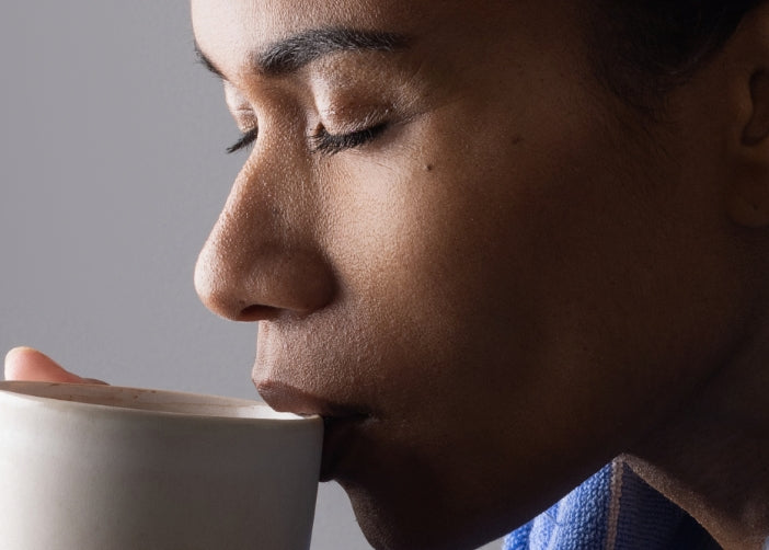 A woman sips a hot cup of Beauty Sleep hot chocolate sleep supplement