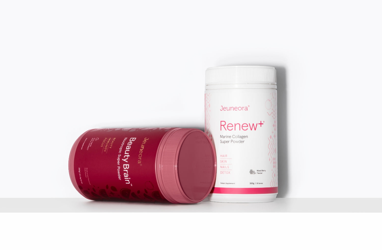 A container of Renew+ Marine Collagen sits on a shelf in front of a white background. A container of Beauty Sleep powder lies on its side in front