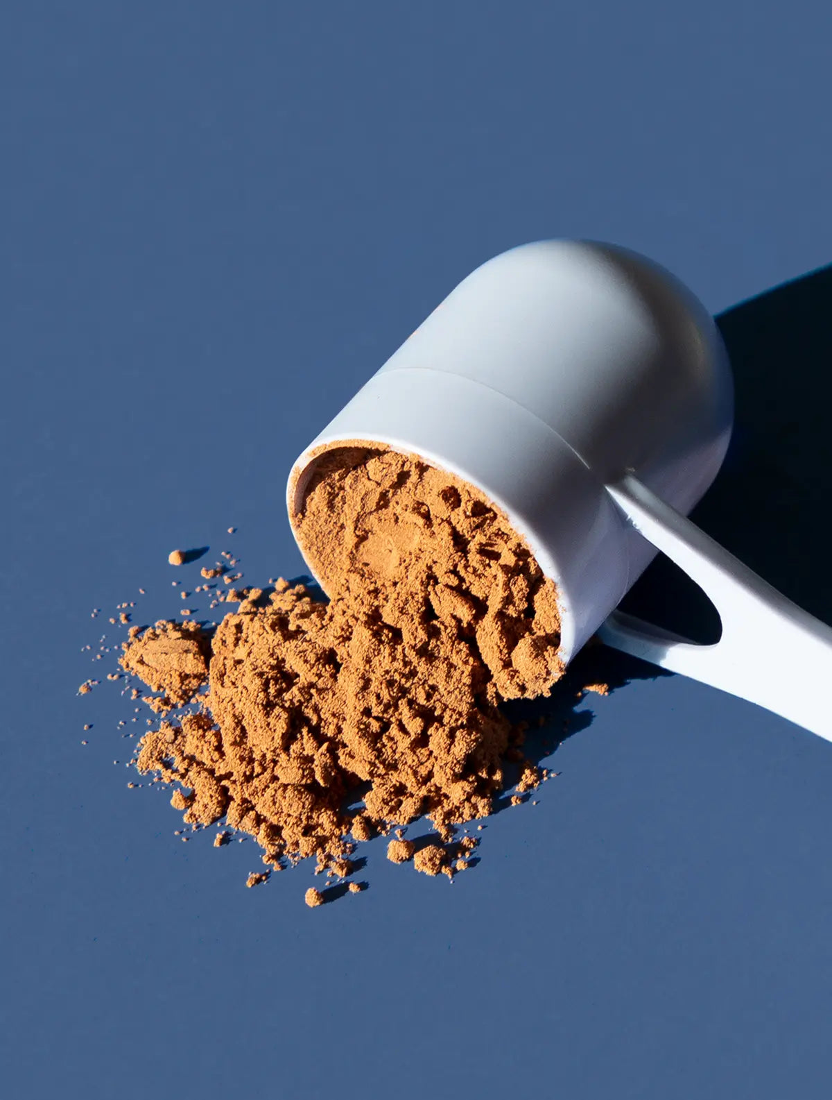 A scoop of Beauty Sleep powder on a blue background.