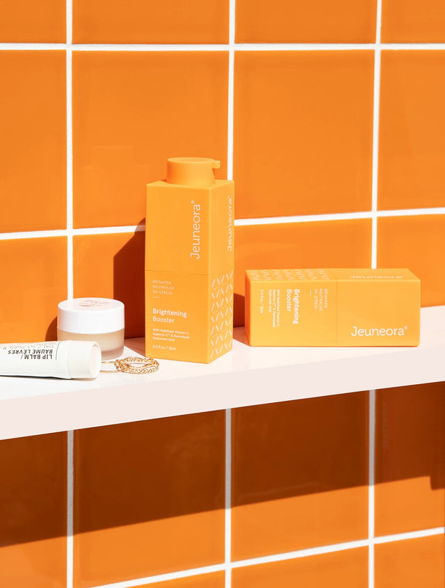 Brightening Booster Double-action Vitamin C Serum sitting on background shelf with orange tiles