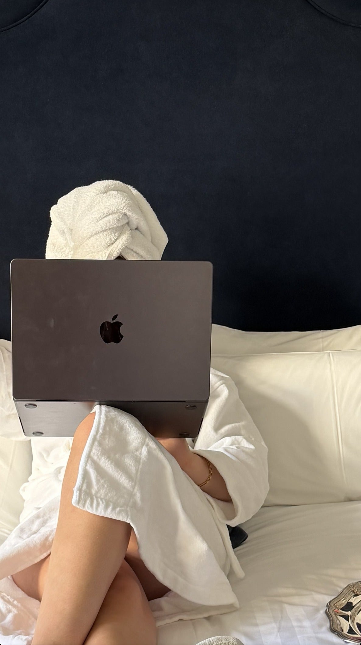 Woman in a hotel robe on the bed shopping on her laptop