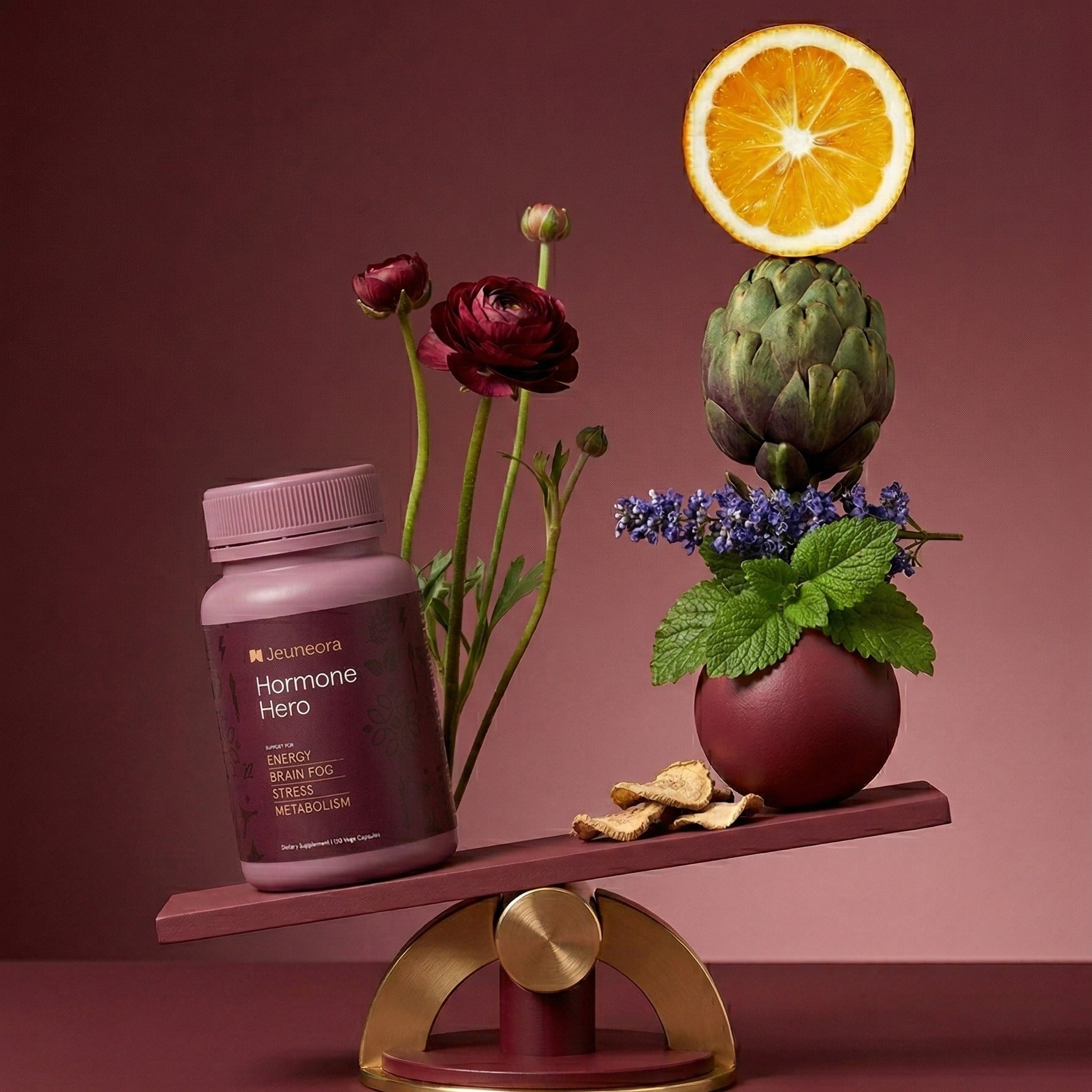 Jeuneora Hormone Hero on a brass balance scale, counterweighted by orange, artichoke, lavender, lemon balm and rhodiola root representing the formula's botanicals.