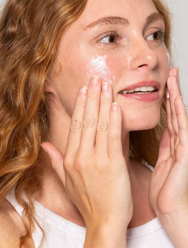Woman rubbing skincare age defying serum onto her face